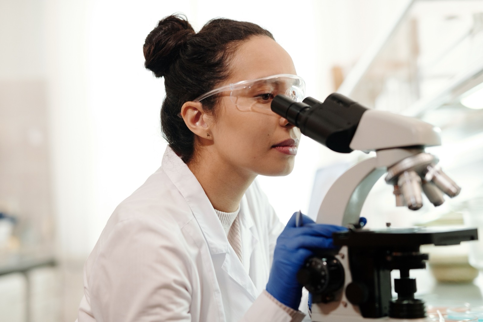 Lab technician at a microscope in an approved testing laboratory, where the drinking water result that decides what to do about Legionella is issued