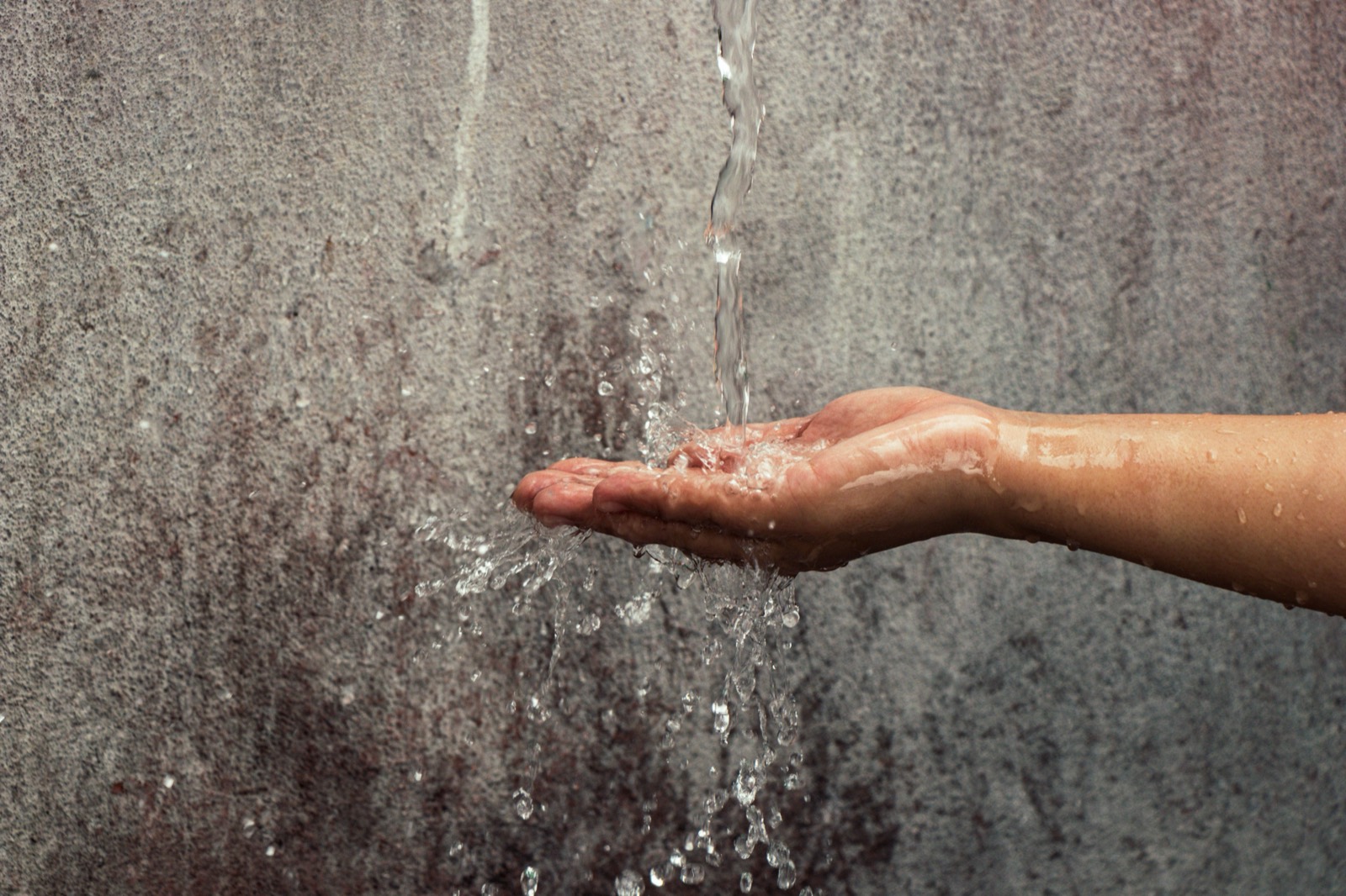 A jet of water hitting a hand, a symbol for drinking water from the tap, Legionella in drinking water